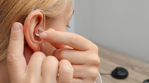 Lady putting hearing aids in.